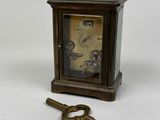a small clock and a key on a white surface