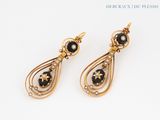 a pair of black and gold earrings on a white surface