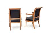 pair of wooden chairs with black upholstered seats against a white background