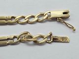 two pieces of gold chain on a white surface