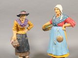 two figurines of women with hats and aprons standing next to each other