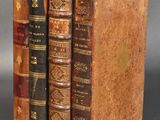 two old books are stacked on top of each other on a table