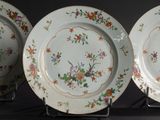 three plates with floral designs are on display on a black surface