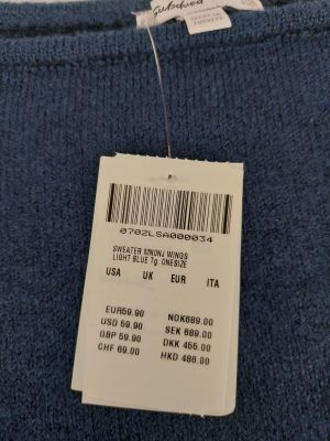 l'étiquette au dos d'un pull bleu est accrochée à un cintre