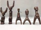 quatre figurines en bois de formes et de tailles différentes, présentées dans une vitrine
