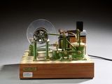 une petite maquette de machine à vapeur posée sur un socle en bois