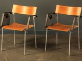two wooden chairs sitting next to each other in front of a gray wall
