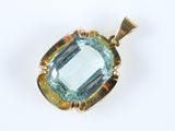 un gros plan d'un pendentif en topaze bleue posé sur une surface blanche