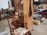 une grande horloge de parquet trônant dans une pièce où se trouve un fauteuil