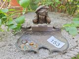 une petite statue représentant un garçon assis sur un rocher