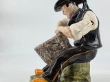 a figurine of a man sitting on a bench reading a book
