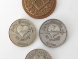 four different coins are shown on a white surface, one is a heart and the other is a compass