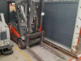 a fork lift truck parked in a warehouse with a truck in the background