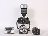 three cameras sitting next to each other on a white surface