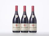 three bottles of red wine are lined up on a table