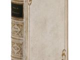 un vieux livre posé sur une table blanche à côté d'un mur blanc