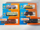 six wagons de train miniature dans leurs boîtes, posés sur une surface blanche