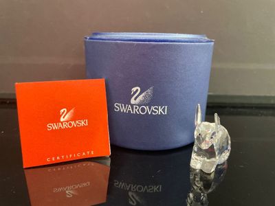 une petite figurine en cristal représentant un cygne, posée à côté d'une boîte de cristaux Swarovski