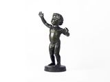 une petite statue en bronze représentant un garçon les mains en l'air