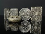 Plusieurs objets anciens en métal argenté sont posés sur une surface noire