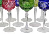 six colorful wine glasses are lined up in a row on a white surface