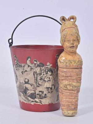un seau rouge avec une statue en bois à côté