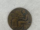 an old bronze coin with a woman sitting on a bench