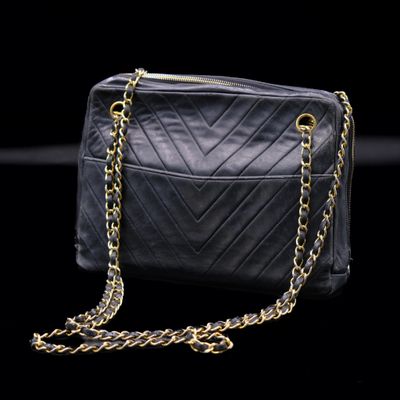 a black purse with gold chains on a black background