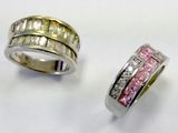 two rings with pink and white diamonds on a white surface