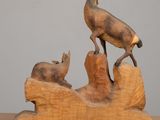 wooden sculpture of a deer and a baby deer on a log
