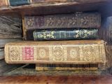 several old books are stacked on top of each other on a shelf