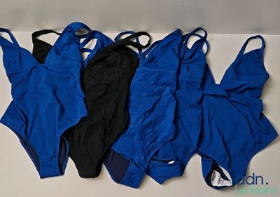 trois maillots de bain bleus et noirs alignés sur une surface blanche