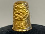 a close up of a gold thimble on a black surface