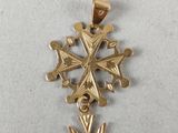 a close up of a gold cross pendant on a white surface