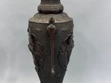 a black vase sitting on a stand on a white background