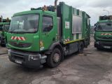 several green garbage trucks parked in a parking lot next to each other