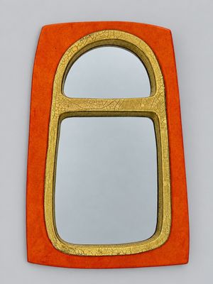 an orange and gold mirror sitting on top of a white wall