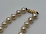 a close up of a pearl necklace on a white surface