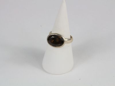 bague en argent ornée d'une pierre marron posée sur un cône blanc