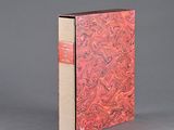 un vieux livre à la couverture rouge posé sur une surface grise