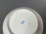 a white plate with a blue flower on it on a table