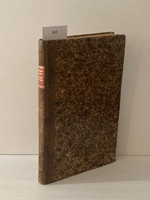 un vieux livre posé sur une table blanche à côté d'un mur blanc