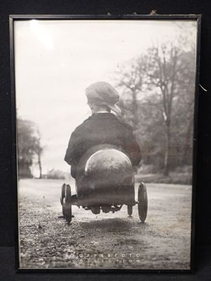 une photo en noir et blanc d'un petit garçon au volant d'une petite voiture