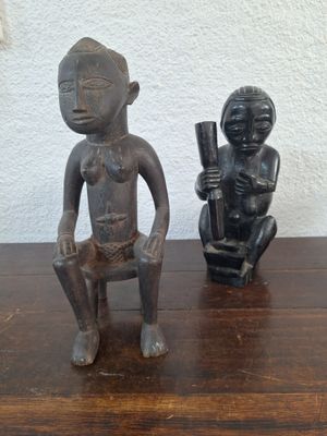two figurines sitting on a table next to each other