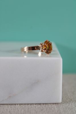 une image représentant une bague en or sertie d'une citrine, posée sur un bloc de marbre