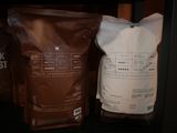 two bags of coffee sitting on a shelf next to each other