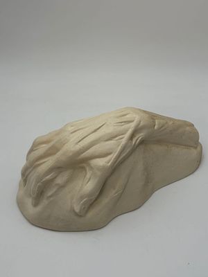 a clay sculpture of a frog on a white surface