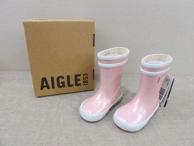 une paire de bottes de pluie roses posées à côté d'une boîte sur une table