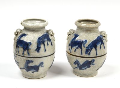 une paire de vases bleus et blancs ornés de chevaux sur un fond blanc