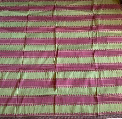 une nappe à motifs roses et verts sur laquelle est assis un chat